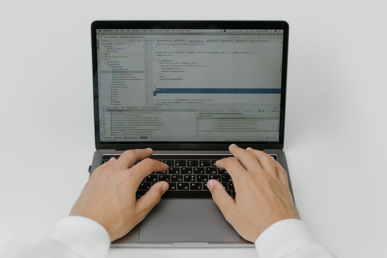 Close-up of hands coding on a laptop, showcasing software development in action.